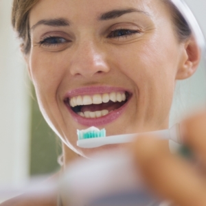 Frau putzt Zähne vorm Spiegel